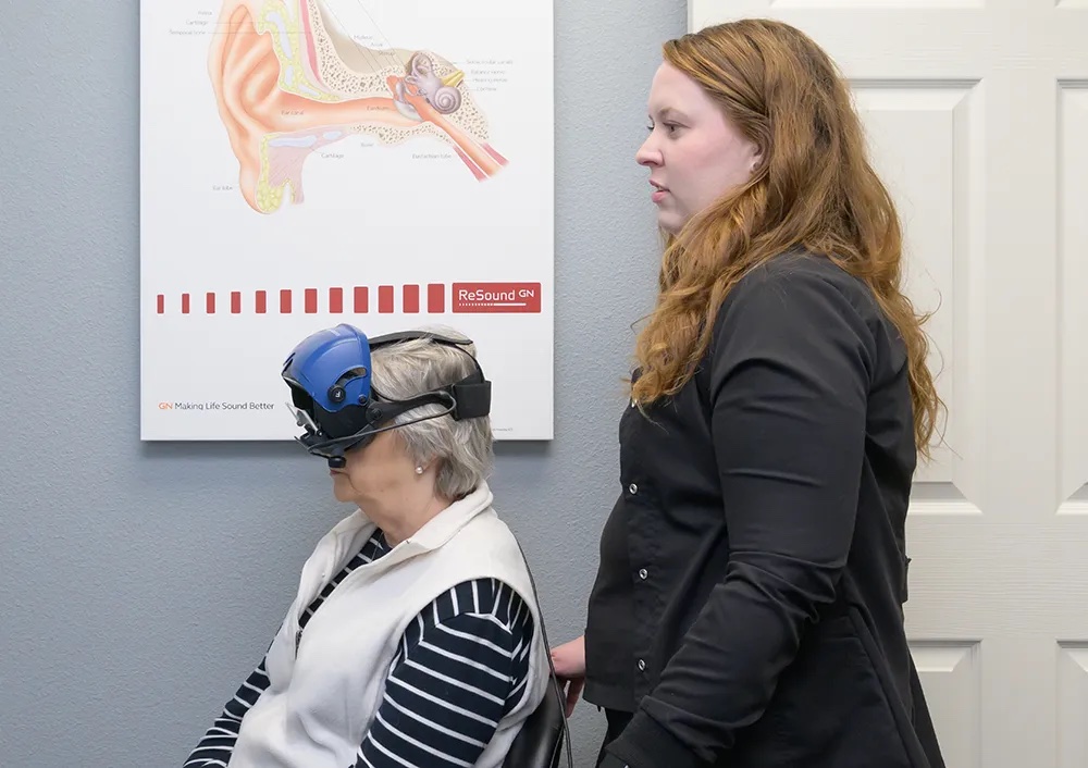 Dr. Staten standing beside a seated patient who wears video goggles for a balance test